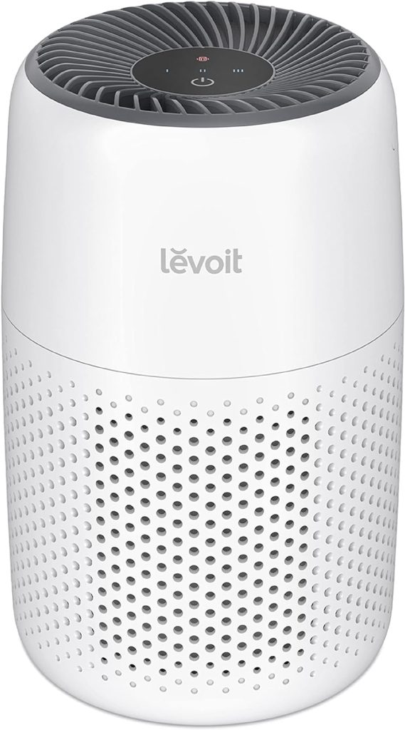 LEVOIT Core Mini-P Air Purifier with a compact, minimalist cylindrical design and a top air outlet, placed in a cozy bedroom for quiet and efficient air purification.